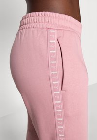 Roze sweatpants met een zachte textuur, elastische tailleband, zijzak en een verticale Puma logo tape-detail langs de buitennaad.