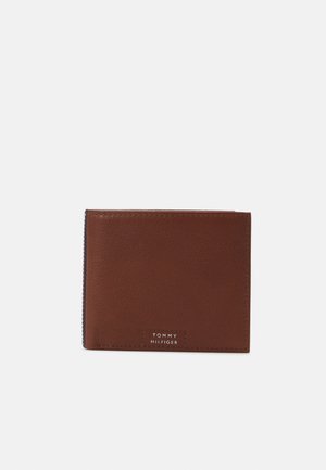 Braunes Lederportemonnaie mit glatter Textur, das vorne mit einem weißen, geprägten "TOMMY HILFIGER"-Logo ausgestattet ist. Kompaktes Design mit genähten Kanten.