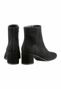 Botines de ante negros con punta redonda y tacón cuadrado. Presentan una cremallera en el lateral y un forro interior suave.