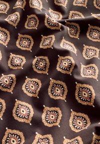 Gemusterter Stoff in Dunkelbraun mit komplizierten floralen Motiven in Gold, Rot und Elfenbein. Glatte Textur mit einem leichten Glanz.