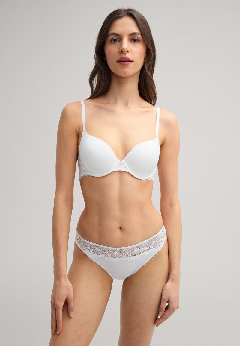 Witte kanten bh en bijpassende slipset. De bh heeft gladde cups met onderkast en verstelbare bandjes; de slip heeft een kanten rand langs de tailleband.