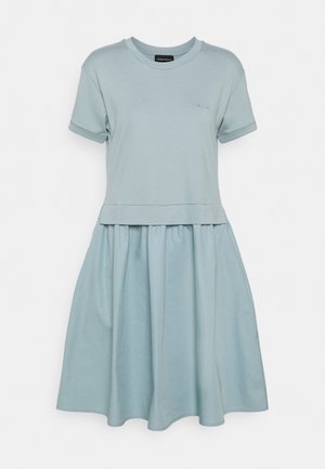 Vestido azul claro de manga corta con escote redondo, parte superior ajustada y falda fruncida que cae por encima de la rodilla. Pequeño logo bordado en el pecho.