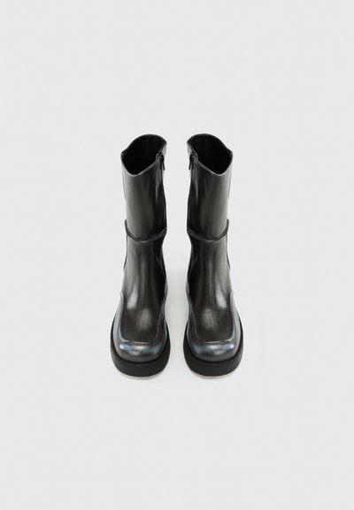 Μαύρα δερμάτινα μποτάκια αστραγάλου με λείο φινίρισμα, αντιθετικές ραφές και στρογγυλεμένη μύτη. Διαθέτουν πλαϊνό φερμουάρ για εύκολο φόρεμα.