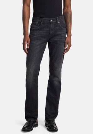 Black denim jeans with a straight-leg design, five-pocket style, and contrast stitching. Worn with black shoes and a fitted black top.