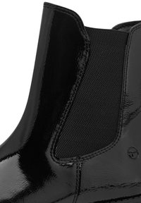 Botte Chelsea en cuir verni noir avec panneau latéral élastique et détails de couture apparents.