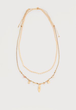 Δύο στρωμένα κολιέ σε χρυσό τόνο, το ένα με μικρούς συνδέσμους σε σχήμα καρδιάς, το άλλο με μαύρο και χρυσό πλεκτό κορδόνι και κρεμαστά γούρια.