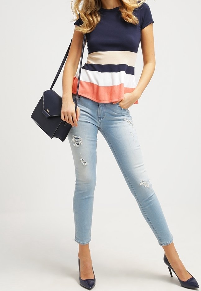 Maglia a righe navy e crema con accenti corallo, abbinata a jeans skinny azzurri strappati. Accessoriata con una borsa a tracolla nera.