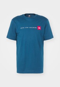 Camiseta de manga corta en algodón teal, con el texto blanco "NUNCA DEJES DE EXPLORAR" y un parche de logo rojo en el lado izquierdo del pecho. Cuello redondo clásico.
