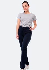 Graues Baumwoll-T-Shirt kombiniert mit marineblauen Jogginghosen, die über einen elastischen Bund und eine Kordel besitzen, ergänzt durch weiße Sneakers.