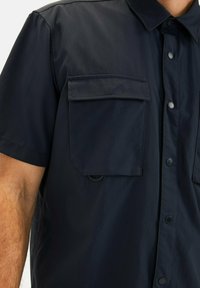 Dunkelblaues Kurzarmhemd mit Button-Down-Kragen, zwei Brusttaschen, Druckknopfverschluss vorne und einem glatten, leichten Stoff.