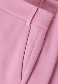 Lichtroze broek van soepel stof, met een vlakke tailleband en zijzakken. De details omvatten nette stiksels en gestructureerde plooien.