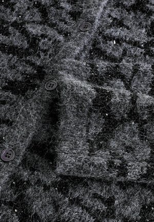 Sivý cardigan s huňatou textúrou, ktorý má čierny tkaný vzor a roztrúsené flitre. Obsahuje dva tmavé gombíky a detailný golier.