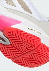 Løpesko med en hvit, strukturell overdel, grå detaljer og en rød, mønstret såle. Har rosa mellomsåle og "CLOUDFOAM+" merke.