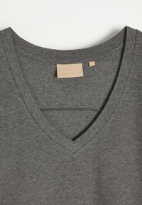 Szary T-shirt z dekoltem w serek, wykonany z miękkiej bawełny z dodatkiem innych włókien. Ma prosty design, gładką fakturę i zawiera małą metkę wewnątrz dekoltu.