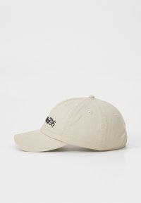 Beige bomull baseball cap med buet skjerm, seks-panel design, og svart brodert tekst "siden 95" foran. Har luftingshull for ventilasjon.