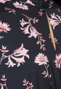 Black fabric with a floral pattern in pale pink and green, featuring a keyhole cutout detail at the neckline and smooth texture.