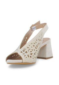 Sandal aperto beige con un design a ritagli geometrici, decorata con piccoli strass. Presenta un tacco a blocco e una cinghia alla caviglia per supporto.