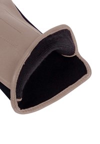Leather glove with a beige outer, black inner lining, smooth texture, and stitched details along the surface and cuff edge.
