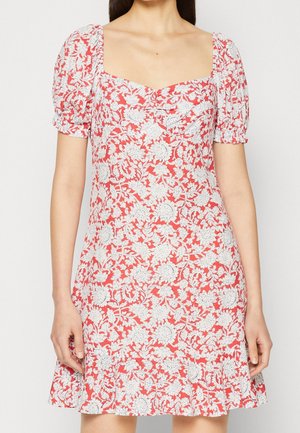 Röd blommig klänning med vita intrikata mönster, fyrkantig halsringning, puffiga korta ärmar och utsvängd nederkant. Tillverkad av lätt tyg.