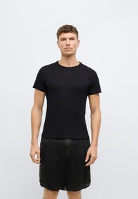 Μαύρο κοντομάνικο t-shirt από απαλό ύφασμα, με στρογγυλή λαιμόκοψη και εφαρμοστή γραμμή, συνδυασμένο με άνετα μαύρα σορτς.