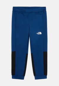 Modre športne hlače iz mehkega blaga z črnimi poudarki na straneh in belim logotipom na desni stegn. Vključuje elastičen pas.