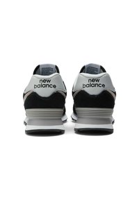 Black and white New Balance sneakers featuring a suede and leather upper, with a cushioned sole and distinct branding on the heel.