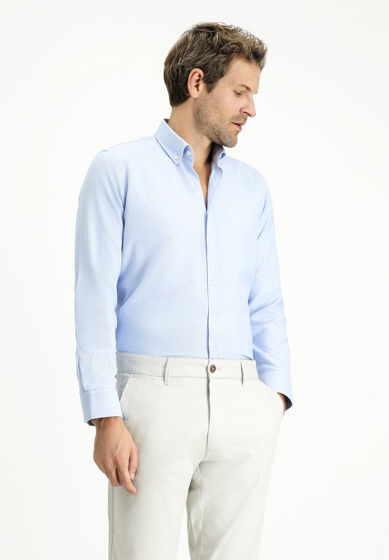 Camicia azzurro chiaro in un mix di cotone testurizzato. Caratterizzata da maniche lunghe, colletto classico e vestibilità slim. Abbinata a pantaloni beige chiaro.