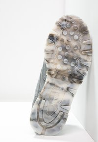 Semelle d'une chaussure Reebok avec une semelle en caoutchouc translucide et marbrée, présentant des motifs circulaires et de profondes rainures pour une adhérence optimale.