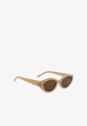 Beige ovale Sonnenbrille mit dicken Rahmen und dunklen Gläsern, mit kleinen dekorativen Punkten nahe den Scharnieren.