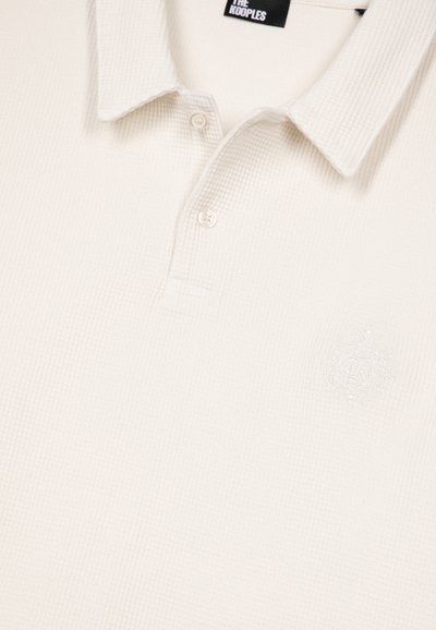 Off-white, gemêleerde polo met een kraag, twee knopen en een subtiele geborduurde embleem op de borst met het label "The Kooples".