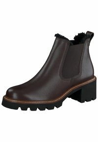 Bota de cuero marrón hasta el tobillo con paneles laterales elásticos, acabado texturizado y una suela de goma negra gruesa. Presenta un borde similar al pelo en la parte superior.