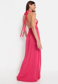 Roosa halter-kleed, millel on seljatuge, elastsest smokkamisest vöökoht ja voogav kangas. Kaela seotavad paelad rõhutavad siluetti.