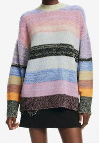 Pull en maille multicolore avec des rayures horizontales en rose pastel, bleu et orange. Légèrement oversize avec un tissu texturé et un col rond.