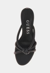 Sandale slingback noire avec un design en avant noué, texture en cuir lisse, semelle intérieure rembourrée et détail de logo sur le semelle.