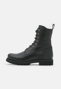 Bottines en cuir noir avec un bout arrondi, dotées d'œillets de couleur dorée et d'une doublure en peluche. Semelle en caoutchouc texturée avec des rainures pour une meilleure adhérence.