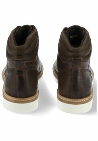 Hnědé kožené kotníkové boty s hladkým povrchem, zaoblenou špičkou, bílou gumovou podešví a dekorativním stehem po stranách.