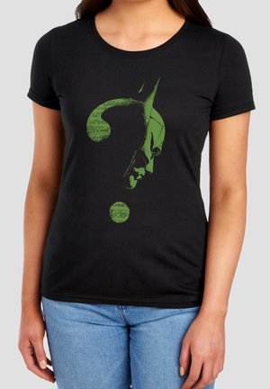 Woman wearing black t-shirt with green question mark shaped as Batman's face and cowl, paired with blue jeans.
