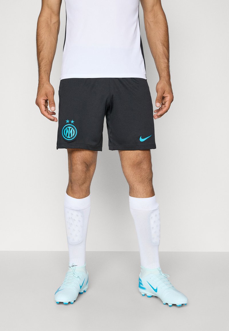 Mustad mustad spordilühikesed püksid türkis sinise Nike logo ja klubi embleemiga, koos valgete sokkidega ja helesiniste jalgpallijalanõudega.
