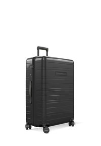 Valise rigide noire avec un design rayé texturé, poignée rétractable et quatre roues pour la mobilité. Fermeture éclair sur le côté supérieur.