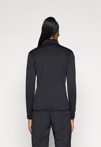 Top nero a maniche lunghe con colletto alto, design aderente e texture liscia. Cuciture visibili lungo la schiena per un dettaglio strutturale.