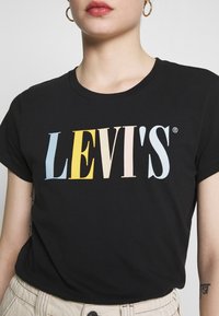 Camiseta de algodón negra con el logo "LEVI'S" multicolor en varios tonos pastel. Mangas cortas y cuello redondo.