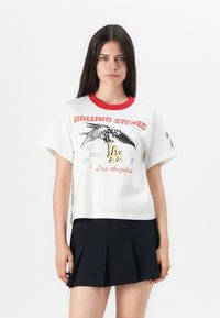 White cotton t-shirt with a red ribbed collar, featuring a graphic print of an eagle, text, and "LA" in yellow. Short sleeves, relaxed fit.