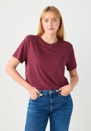 Bordowa bawełniana koszulka z krótkimi rękawami, okrągłym dekoltem, luźnym fasonem, połączona z wysokim stanem niebieskich dżinsów.