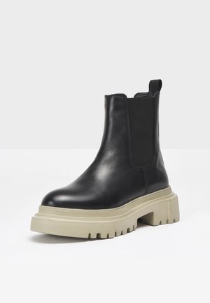 Stivaletti Chelsea in pelle nera con pannelli laterali elastici, suola in gomma spessa color crema, punta arrotondata e linguetta sul tallone.