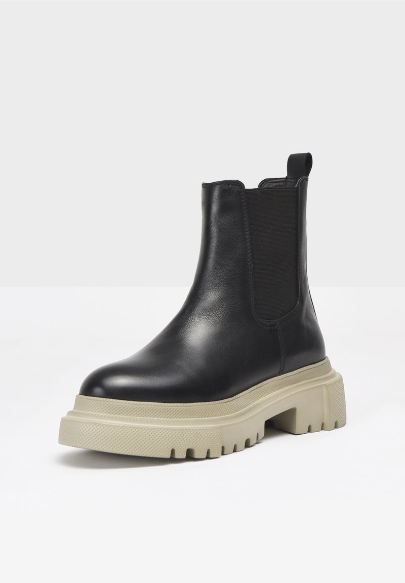 Black leather chelsea boot with elastic side panels, thick cream-colored rubber sole, rounded toe, and pull tab on the heel.