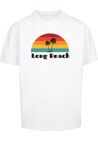 Valkoinen T-paita, jossa on graafinen kuvasto, jossa on sateenkaaren auringonlasku ja kaksi palmupuuta. Alapuolella oleva teksti lukee "Long Beach" paksuilla mustilla kirjaimilla.