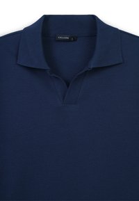 Polo di colore blu navy con un motivo testurizzato a nido d'ape. Presenta un colletto classico e un design a scollo a V. Etichetta di taglia L visibile.