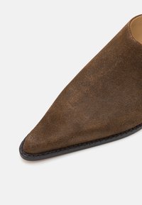 Brun samtspiss sko med teksturert overflate og svart gummisåle. Designet har en sømløs overdel og smal tå.
