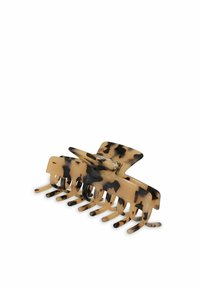 Skalbagge i sköldpaddsmönster med glänsande yta, har en central öppning och flera böjda taggar för ett säkert grepp om håret.