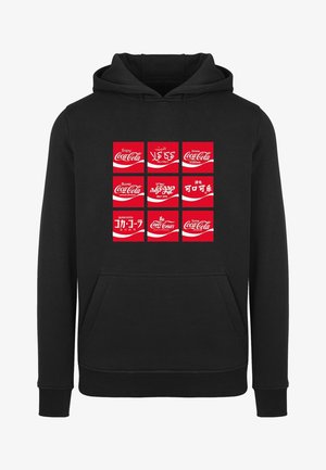 Sudadera negra con una cuadrícula de logotipos de Coca-Cola en rojo en varios idiomas. El diseño incluye un bolsillo frontal y puños y dobladillo de canalé.